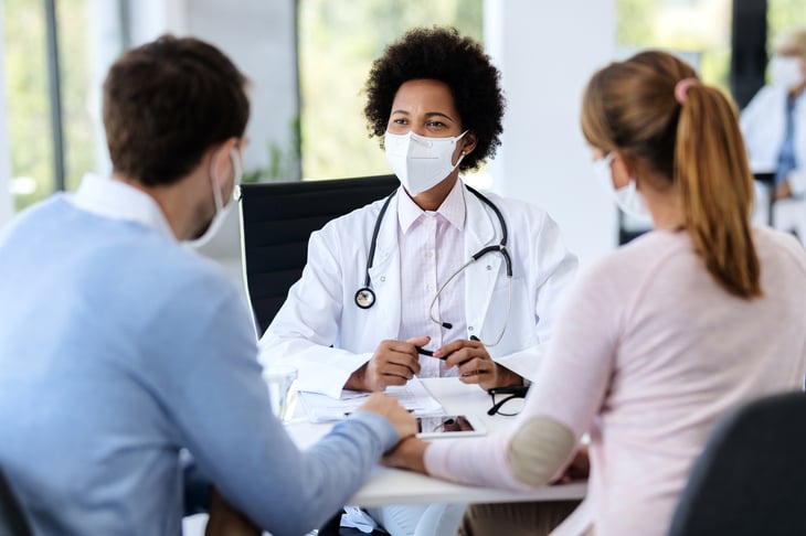 African-American-doctor-wearing-protective-face-mask-during-an-appointment-with-a-couple-at-clinic.-1270585289_2125x1416 (1)