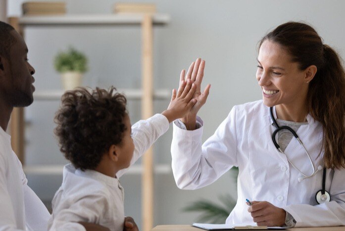 Paciente infantil encostando na mão da pediatra, sucesso médico em indicadores de performance