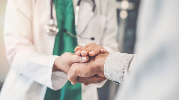 Médico segurando na mão de paciente idoso