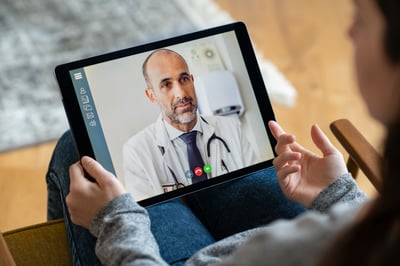 Médico atendendo paciente por tablet via telemedicina